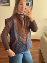 Chaleco acolchado con frente de cuero marrón y espalda de tela azul con diseño de rombos.