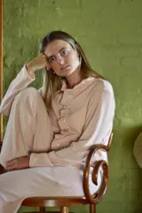 Conjunto de pijama rosado a rayas verticales, compuesto por una camisa de manga larga con cuello con volados y botones, y un pantalón recto con elástico en la cintura.