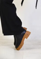 Botas negras de cuero con suela track color caramelo.