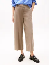 Pantalón de vestir color beige, de corte tobillero y pierna ancha. Confeccionado en tejido antiarrugas de mezcla de poliéster, viscosa y elastano. Presenta cierre de cremallera con enganche oculto, raya marcada en la parte delantera y trasera, y dos bolsillos traseros de ojal.