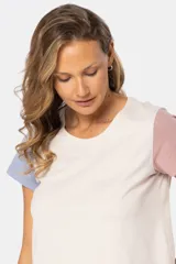 Remera de manga corta y cuello redondo, con bloque de color: cuerpo color crema, manga derecha color rosa y manga izquierda color celeste.