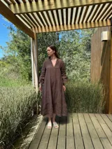 Vestido largo color marrón chocolate, de lino, con cuello mao y escote en V. Presenta corte escalonado con volados en el ruedo y mangas largas con puños elásticos.