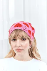 Bandana tejida a crochet, con base rosa y diseño de corazones rojos.