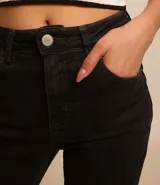 Pantalón boot cut de jeans negro, con bolsillos delanteros y traseros, cierre con botón y cremallera, y trabillas en la cintura.