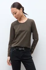 Remera de manga larga color verde oliva, con cuello redondo y botones decorativos en los puños.