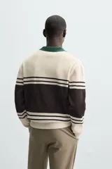 Polo de hombre relaxed fit, tejido en hilatura con textura chenilla. Presenta cuello solapa con cierre frontal de botonadura, manga larga y acabados en rib. Diseño a rayas horizontales en color crema y negro, con cuello en verde oscuro.