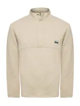 Buzo color beige con cuello alto y cierre de snaps. Diseño de rombos y parche con logo de la marca en el pecho.