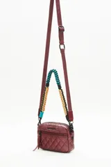 Bandolera negra de nylon matelassé con correa larga regulable y correa corta desmontable de cordones trenzados multicolores. Tiene cierre superior, bolsillo frontal con cierre, bolsillo trasero y dos bolsillos internos.