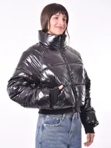 Campera puffer corta color negro brillante, con cuello alto, cierre frontal y puños ajustados.