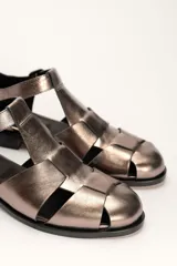 Sandalia roja de cuero vacuno con diseño de tiras entrecruzadas y hebilla lateral. Tiene suela de cuero artesanal y taco bajo.
