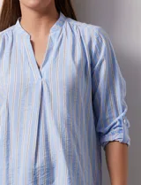 Blusa beige con rayas verticales blancas, escote en V y mangas 3/4 regulables con presilla y botón.