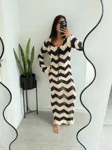 Vestido largo de tejido de punto calado con diseño de zigzag en blanco y negro, escote en V con cordones ajustables y mangas largas acampanadas.