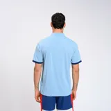 Remera polo celeste con detalles en azul marino en cuello y mangas. Escudo del Club Nacional de Football bordado en el pecho y logo de Umbro estampado en blanco.