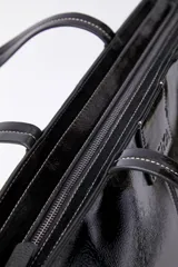 Bolso grande de cuero ecológico negro, con interior forrado en algodón y un bolsillo con cierre.