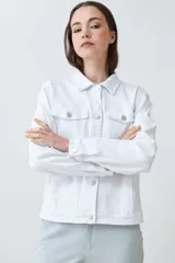 Campera de jean blanca con cuello clásico, bolsillos con solapa abotonados en el pecho y cierre frontal con botones metálicos. Corte recto.