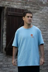 Remera negra de algodón con cuello redondo y mangas cortas. Estampado pequeño en el pecho con un diseño abstracto en tonos naranja y amarillo.