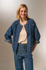 Campera de jean azul con manga larga, corte holgado, cuello redondo y cierre frontal con botones. Presenta bolsillos delanteros y detalles de ojales metálicos.