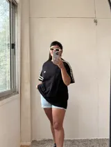 Remerón negro de algodón con mangas cortas y detalle de dos tiras horizontales blancas en las mangas.