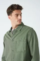 Sobrecamisa verde militar de algodón grueso tipo canvas, con cuello clásico, cierre frontal con botones, dos bolsillos de parche en el pecho con solapa abotonada y dos bolsillos de parche en la parte inferior.