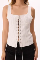Corset blanco con finas rayas verticales negras, escote recto y ajuste frontal con cordones entrelazados.