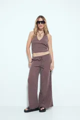 Pantalón de tiro bajo, calce relajado y pierna amplia, color marrón oscuro con textura acanalada. Presenta cintura ajustable con lazo.