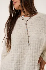 Buzo oversize color beige confeccionado en tejido sintético con destellos de lurex, cuello redondo y manga larga.