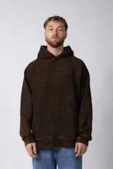 Buzo canguro marrón con capucha, confeccionado en frisa gruesa de algodón con recortes y calce oversize.