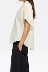 Camisa corta color crema de 100% algodón con cuello camisero y manga corta murciélago. Cierre frontal con botonadura.