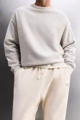 Sudadera de entrenamiento color gris claro, de corte relaxed fit, confeccionada en tejido de algodón con interior de rizo. Tiene cuello redondo, manga larga y acabados en rib.