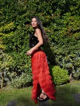 Falda larga color verde oliva con múltiples capas de flecos largos, creando un efecto texturizado. La falda tiene un tajo lateral.