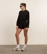 Campera deportiva cropped color negro, con capucha y mangas largas. Presenta cierre frontal, detalle reflectante y está confeccionada en tejido tecnológico.