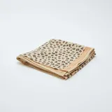 Pañuelo cuadrado de tela color beige con estampado de manchas de leopardo en marrón y negro.