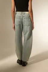 Pantalón de jean negro de corte ancho y tiro bajo, con detalles de tachas metálicas en los bolsillos delanteros y a lo largo de las costuras laterales.