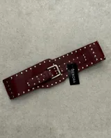 Cinto faja color bordeaux con tachas plateadas y hebilla metálica.