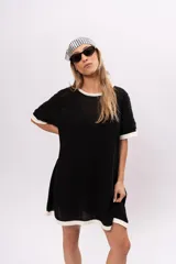 Vestido corto negro de tejido de punto calado, con cuello redondo y mangas cortas con ribete blanco.