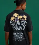 Remera negra de algodón con efecto desteñido (stone wash), corte boxy y manga corta. Estampa grande en la espalda con cinco calaveras amarillas y texto en blanco que dice "SAVAGE SQUAD" y debajo "WE WERE NEVER QUIET".