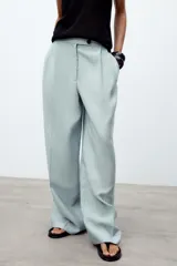 Pantalón de tiro medio color celeste confeccionado en hilatura con mezcla de lyocell. Tiene bolsillos laterales, pinzas delanteras, pierna ancha y cierre frontal con cremallera y botón.