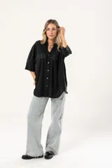 Camisa negra con calados, escote en V, abotonada y manga 3/4.