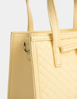 Cartera mini city color amarillo claro, de cuerina trenzada, con doble asa corta de mano, correa regulable desmontable, cierre superior y moño decorativo.