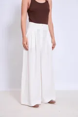 Pantalón palazzo de lino color crudo, con cintura alta y pinzas delanteras.