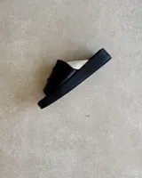 Sandalia de cuero vacuno color negro con tira ancha sobre el empeine y base plana.