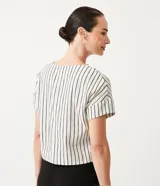 Blusa de algodón color blanco con rayas verticales negras, cuello redondo y botones decorativos en los hombros.