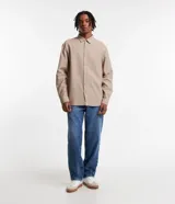Camisa beige de tricolina texturizada, corte amplio, manga larga y abotonada al frente.