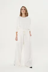 Pantalón palazzo color crudo, de morley térmico suavizado, con bolsillos laterales, cintura elastizada y cordón ajustable.