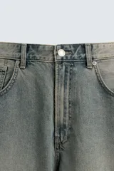 Pantalón de jeans de algodón, corte baggy fit, tiro medio, con efecto lavado en tonos grises y verdes. Presenta cinco bolsillos y cierre frontal con cremallera y botón.