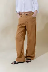 Pantalón de lino rústico color marrón, de calce recto y tiro medio. Tiene bolsillos delanteros y traseros. En el ruedo presenta un ojalillo de marca.