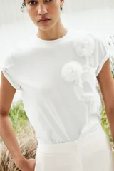Camiseta blanca de algodón de manga corta y cuello redondo con detalle de flores en relieve en el frente.