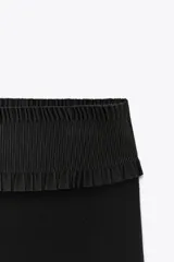 Pantalón negro de tiro medio, confeccionado en tejido elástico con cintura elastizada y corte acampanado.