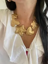 Collar dorado con cadena y dijes colgantes con formas de corazón, estrella y flor.