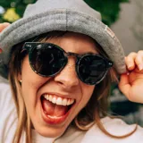 Lentes de sol redondos con montura de acetato con estampado de hojas en tonos verdes y grises. Lentes grises y patillas con el logo de la marca Indie. Hechos a mano y sustentables.